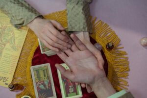 Mystical scene with a fortune teller reading tarot cards and examining a palm for insights.